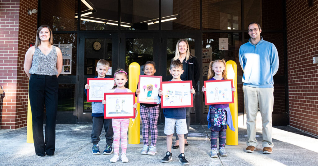 A group of elementary school students holding up their safety oriented drawings