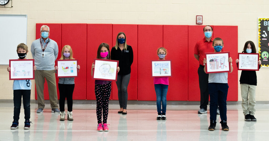 A group of elementary school students holding up their safety oriented drawings