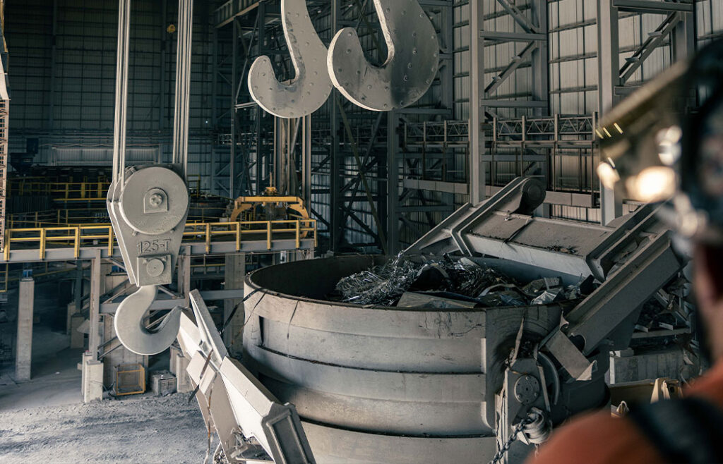 A melt shop crane operator lifts bucket of scrap with a Morgan charge crane.