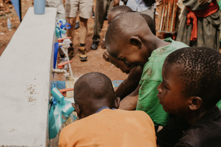 Children in Africa getting clean drinking water from a well