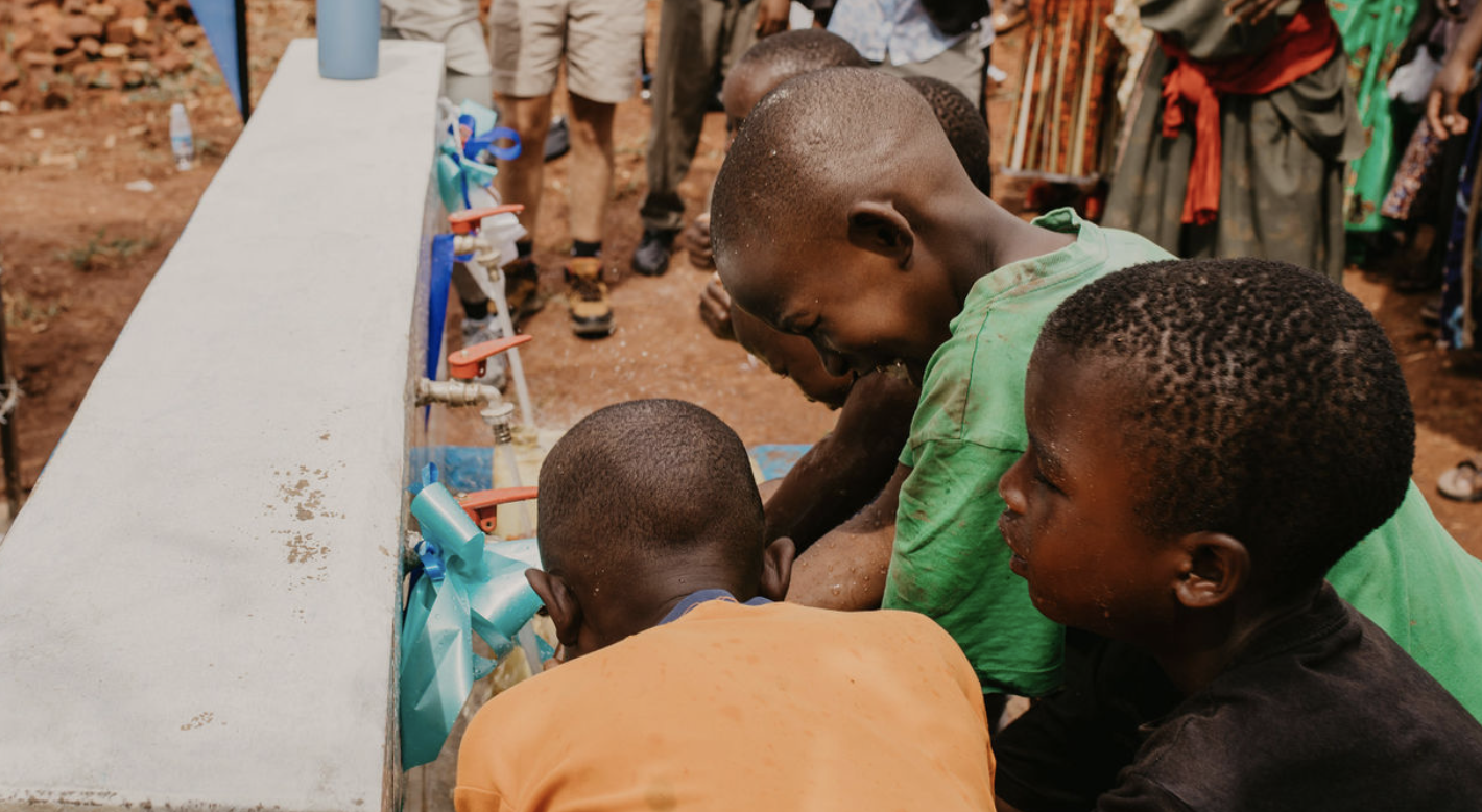 Children in Africa getting clean drinking water from a well