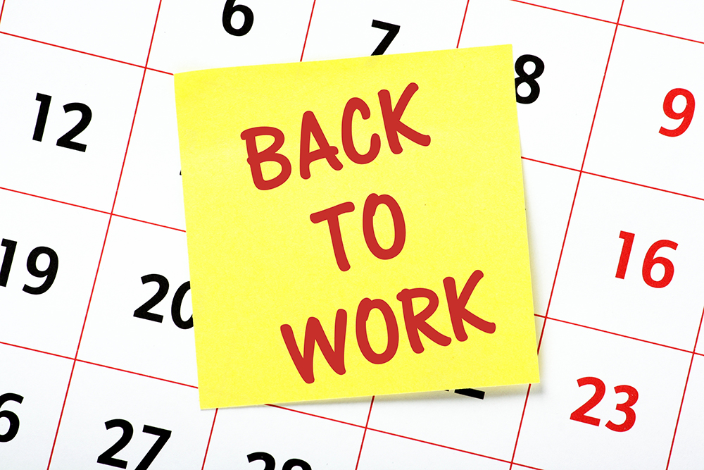 A sticky note over a calendar with the words "Back to Work" written on it