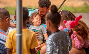 A local happy family with three children gathered around sharing laughter and talking to one another.