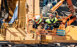 Two Morgan Site Service Team employees on an orange boom lift during a crane installation.