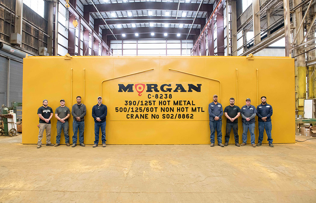 Eight men standing in front of a newly assembled Morgan crane