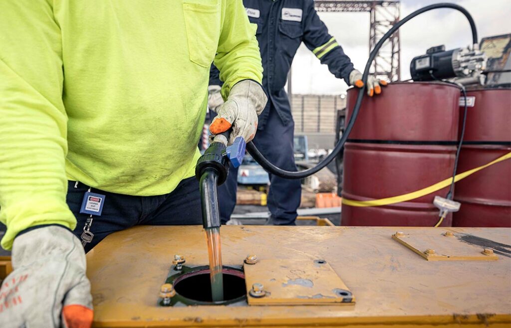 Crane technicians prepare crane for installation by filling oil in gearbox