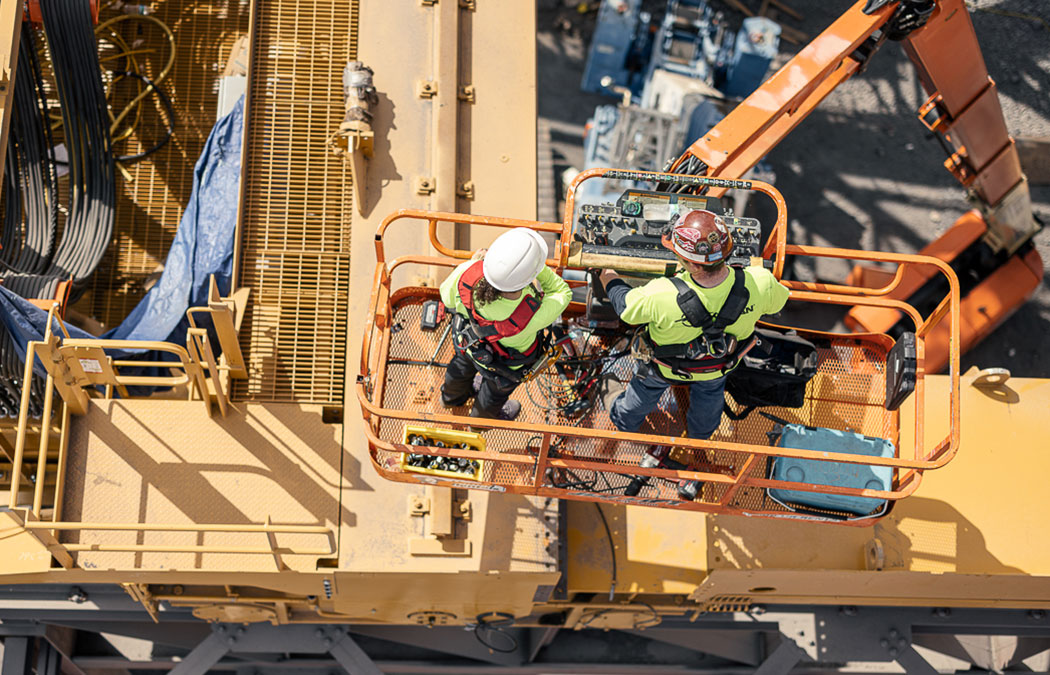 Two Morgan employees installing a crane from a boom lift