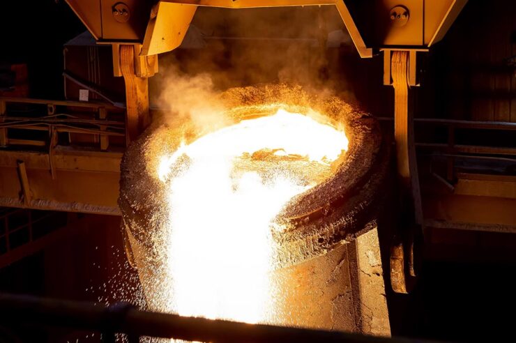 Glowing orange molten steel being poured out of a ladle crane.