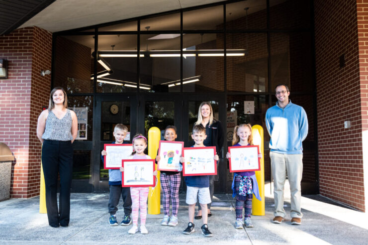 Young children holding up their artwork for the safety drawing contest