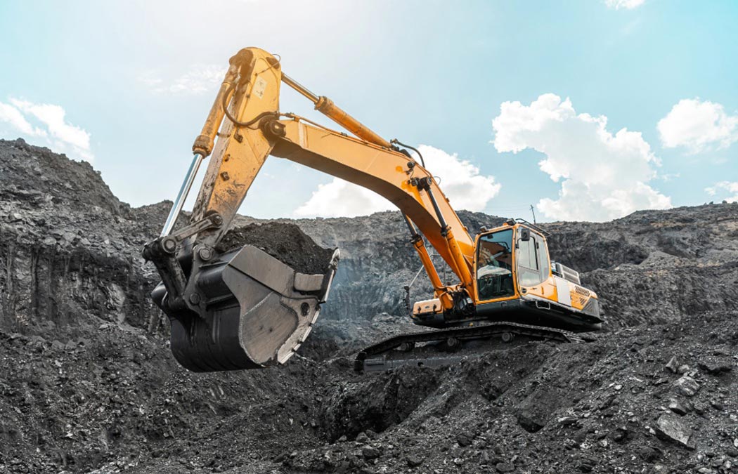 Excavator digging a hole in a rocky hillside.